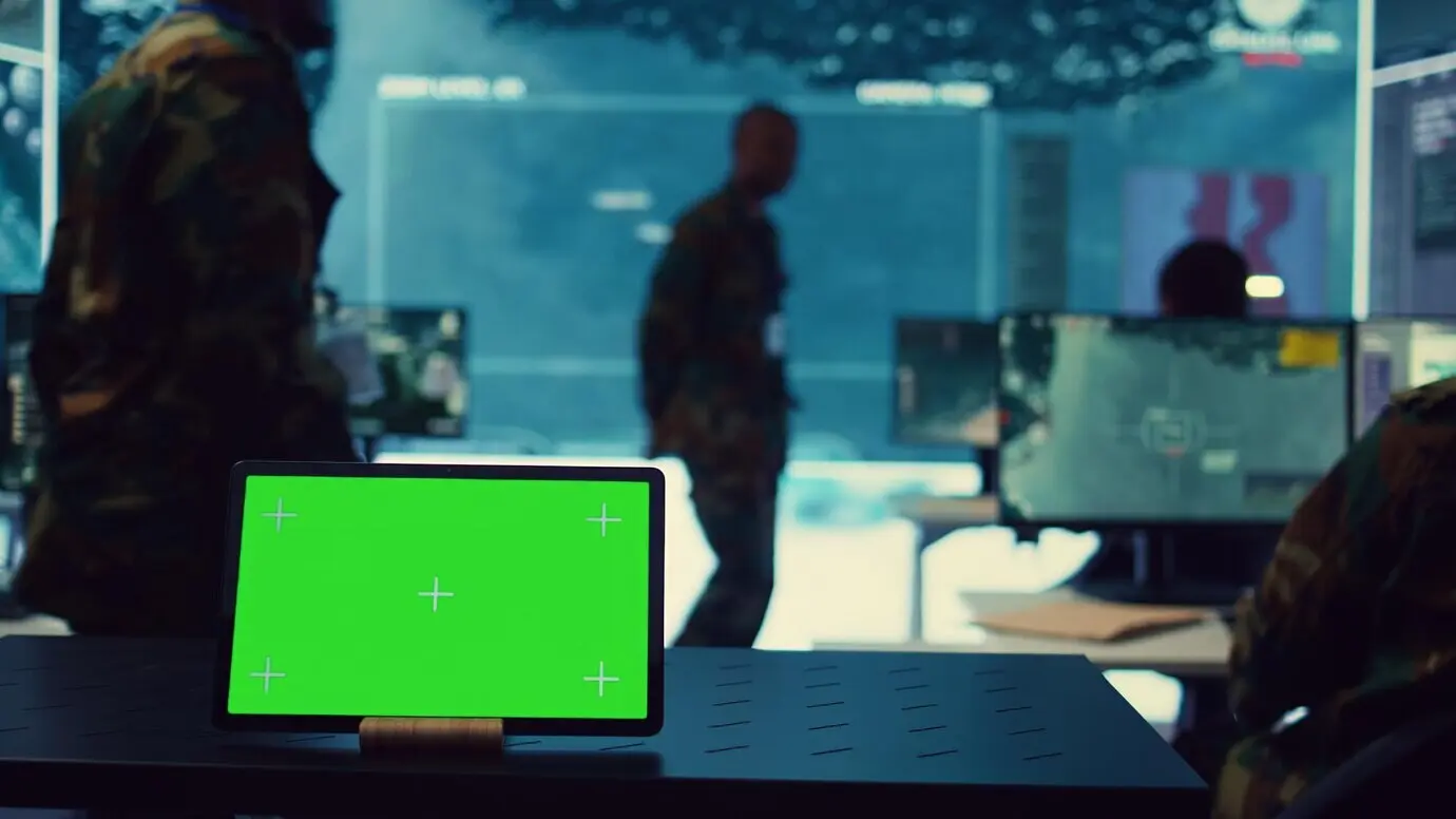 Tableta con pantalla de fondo verde funcionando en un puesto de mando, base de operaciones.
