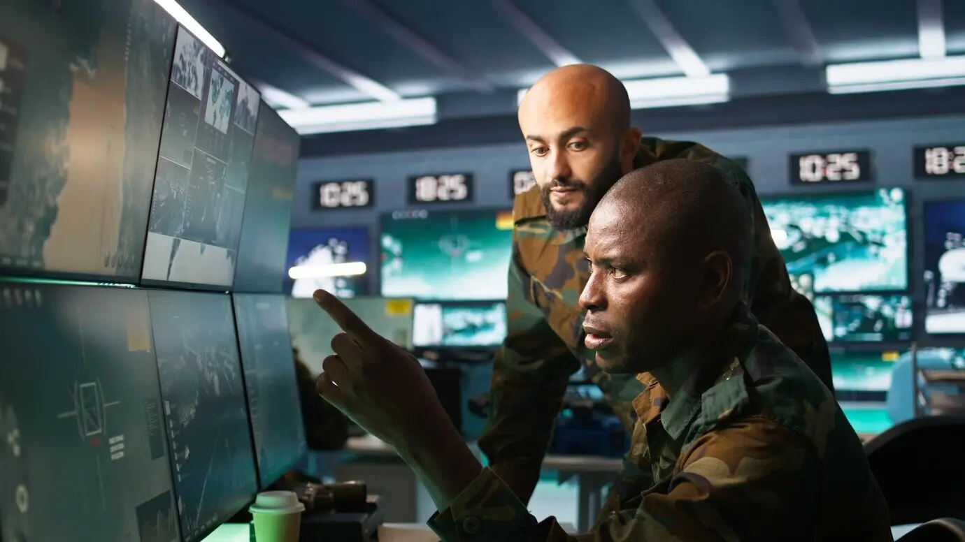 Soldados militares utilizan dispositivos de radar para observar zonas de asalto en pantallas.